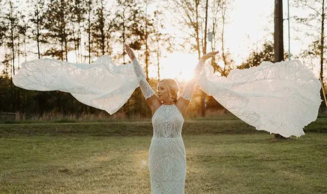 A woman in white dress holding up her arms.